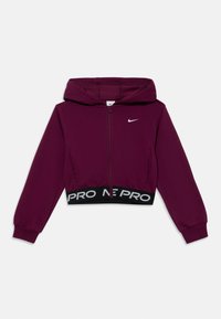 Ciemnofioletowy, krótki hoodie z zamkiem błyskawicznym, długimi rękawami, czarnym elastycznym pasem z napisem "NIKE PRO" i małym białym logo Nike na klatce piersiowej.