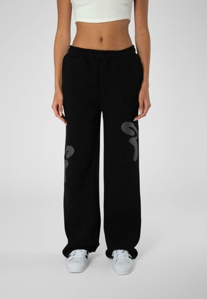 Schwarze Jogginghose mit lockerer Passform, die an der Vorderseite graue abstrakte Muster aufweist. Aus weichem Stoff mit einem elastischen Bund.