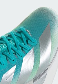 Αθλητικό παπούτσι ελαφρού βάρους με επάνω μέρος από διχτυωτό ύφασμα σε τιρκουάζ απόχρωση, ασημένιες λεπτομέρειες, υφή με σχέδιο και επίπεδα κορδόνια. Ξεκάθαρη σήμανση επωνυμίας στη γλώσσα.