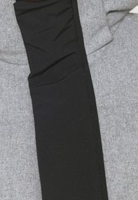 Chaqueta de tela gris con un panel lateral negro y suave. La textura es suave con un aspecto ligeramente jaspeado y detalles de costura visibles.