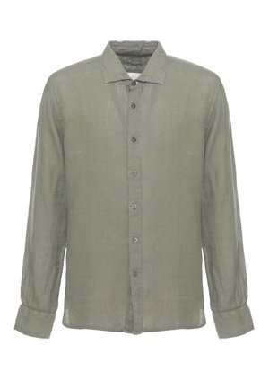 Uomo in piedi con camicia verde oliva a maniche lunghe abbottonata, pantaloni panna e sandali marroni su sfondo bianco.