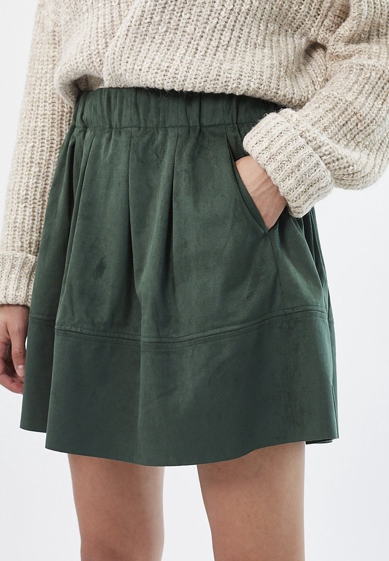 Jupe plissée verte en tissu texturé doux, dotée d'une taille élastique et de poches latérales.
