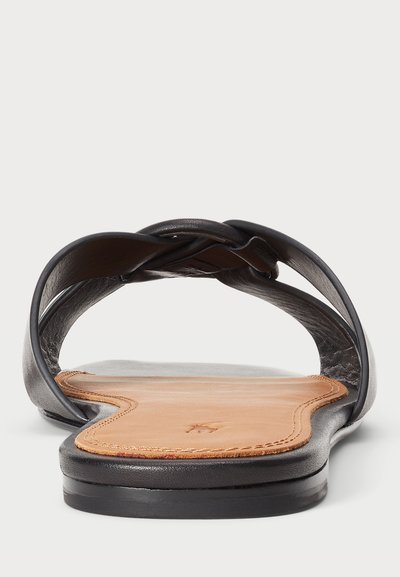 Sandal de slide em pele preta com parte superior trançada, palmilha suave em tom de tan e sola plana preta. Projetado para facilidade e conforto ao calçar.