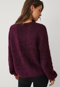 Wolblend trui in diep paars met een textuurrijke, pluizige oppervlakte, losse pasvorm, brede halslijn en lange mouwen.