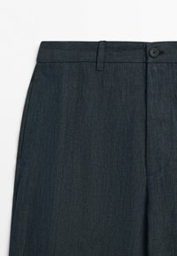 Dark blue tailored trousers with a waistband, belt loop, side pocket, button closure, and straight leg fabric visible.