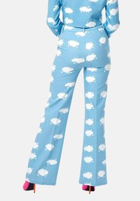 Blue flared pants made of fabric with a cloud pattern in white. Features a fitted waist and distinctive pink and black heeled shoes.