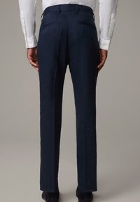 Marina byxor med en texturerad tyg, i rak modell, två bakfickor och en skräddarsydd passform, kombinerade med en vit skjorta med långa ärmar.