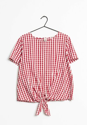 Rood-wit geruit blouse met korte mouwen, ronde halslijn en knoopdetail aan de voorkant, hangend aan een zwarte hanger tegen een witte achtergrond.