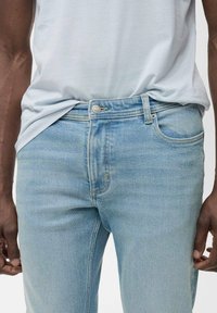 Lichtblauwe denim jeans met een slim fit, voorzien van een voorzak, subtiele stiksels en een zilveren knoopsluiting. Zacht, gestructureerd materiaal.