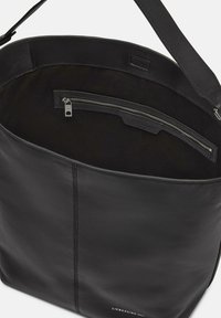 Schwarze Leder-Tote mit glatter Textur, großer Öffnung und einem Innenfach mit Reißverschluss. Subtile Steppnähte an den Seiten.