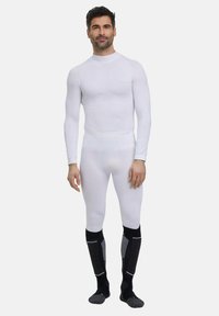 Ensemble de sous-vêtements thermiques blancs comprenant des manches longues et une coupe ajustée, avec une taille élastique. Accompagné de chaussettes montantes noires et grises.