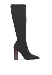 Botte noire en tricot montant jusqu'au genou avec un bout pointu et un talon bloc en bois épais. Présente une texture côtelée et un design sans coutures.