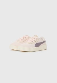 Niske tenisice u pastelno ružičastoj boji s kremastim rebrastim potplatima i mauve Puma prugama na jednostavnoj bijeloj pozadini.