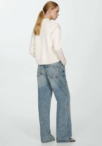White cropped sweater with a round neckline, paired with light blue wide-leg jeans featuring a faded wash and back pockets.