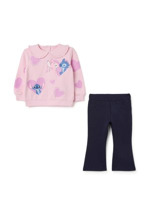 Rosa Sweatshirt mit Rüschensaum, verziert mit Grafiken von Figuren und Herzen. Kombiniert mit dunkelblauen Schlaghosen.