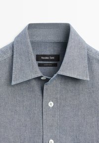 Šedá chambray košile na knoflíky s hrotovým límcem, vybavená zářezem na légě a značkovou štítkem „Massimo Dutti“ uvnitř límce.
