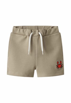 Beżowe szorty dla małego dziecka z elastycznym pasem, białym sznurkiem do regulacji, bocznymi kieszeniami oraz małym czerwonym haftem kraba na przedniej, prawej nogawce.