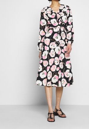 Robe noire enveloppante à manches longues, présentant un motif floral rose et blanc. Inclut une ceinture assortie et est de longueur genou.
