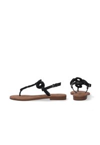 Sorte flade sandaler med et flettet stropdesign, der har en løkkeaccent og en justerbar ankelspænde. Suede-lignende struktureret sål.