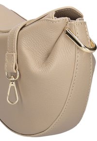 Beige leren handtas met een gladde textuur, gebogen vorm en goudkleurige hardware. Beschikt over een lusvormige schouderband en een geplooide sluiting.