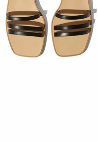Sandalias negras con tiras, que cuentan con tres tiras paralelas, un diseño de punta cuadrada y una plantilla en tono beige neutro. El material parece suave y elegante.
