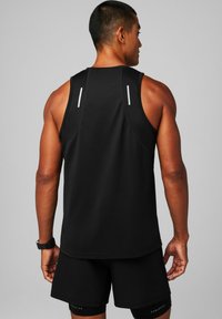 Black athletic tank top with a mesh texture, featuring reflective accents on the shoulders. Worn with matching black shorts.