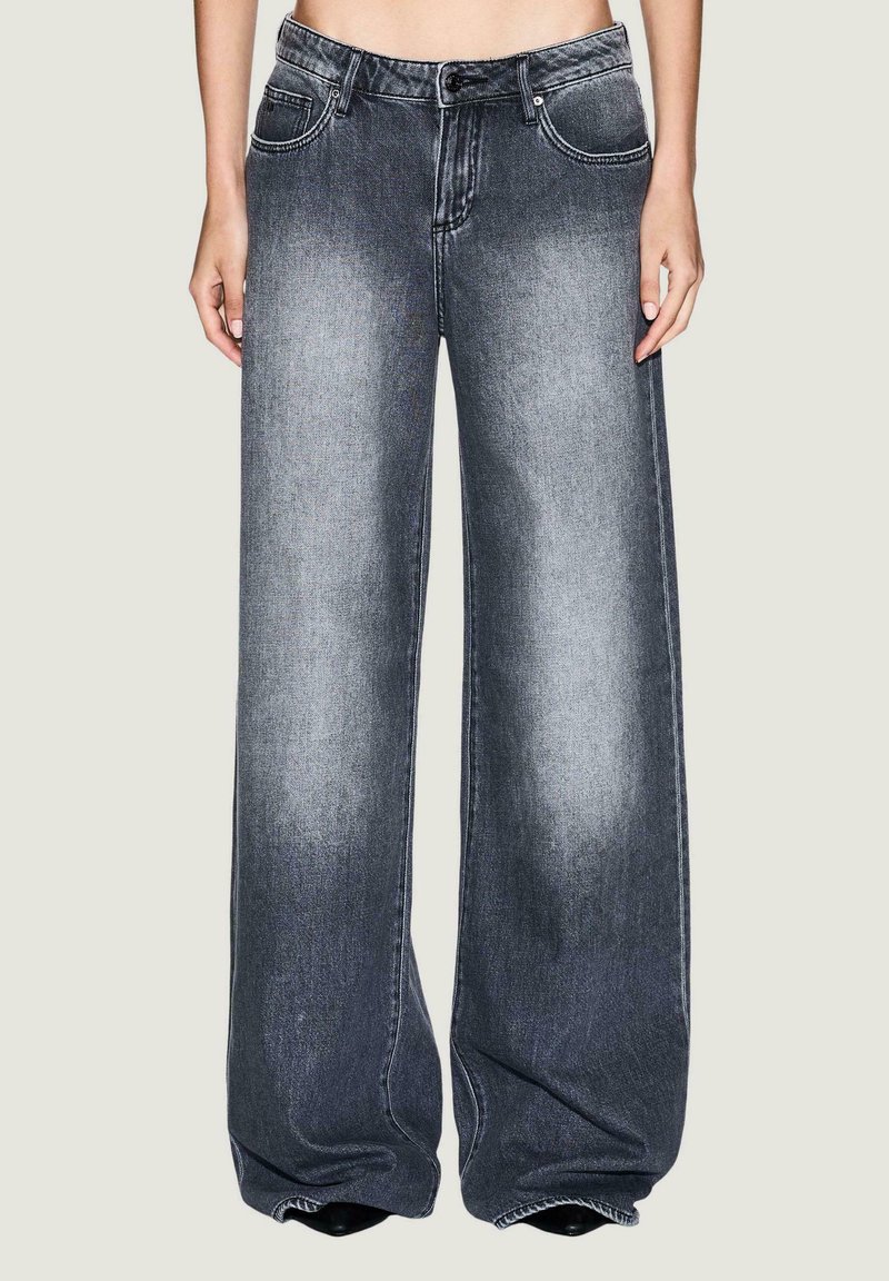 Jeans de pierna ancha hechos de mezclilla gris oscuro, con una textura desvanecida, cinco bolsillos y cierre de cremallera. Las piernas se estrechan ligeramente hacia el dobladillo.
