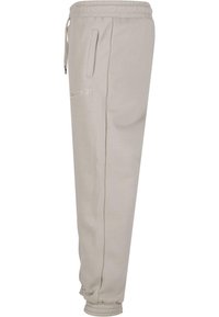 Light beige sweatpants made of soft fabric, featuring side pockets, an elastic waistband with drawstring, and ribbed cuffs.