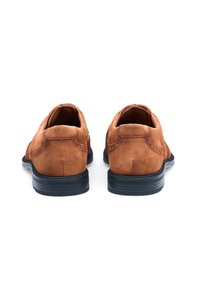 Bruine suède schoenen met een soepele textuur, ronde neus en een zwarte rubberen zool. Stikdetails langs de naden, minimalistisch ontwerp.