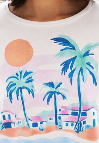 Camiseta blanca con una colorida escena de playa que incluye palmeras, un sol y casas estilizadas en tonos pastel de azul, rosa y melocotón.