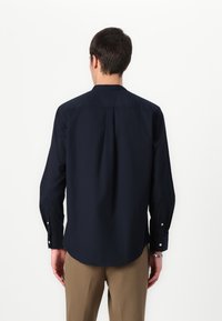 Camicia blu navy con maniche lunghe e piega posteriore, realizzata in tessuto liscio. Presenta polsini con bottoni e orlo curvo. Vestibilità slim.