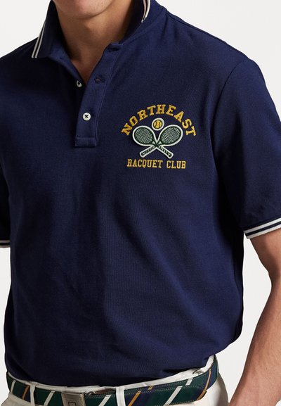 Navy polo shirt with white striped collar, featuring yellow and green embroidery of two tennis rackets and "NORTHEAST RACQUET CLUB."