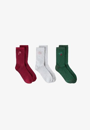 Satz von drei urlaubsbezogenen Socken: burgunderrot mit einem Zuckerstangenmuster, hellgrau mit einer Schneeflocke und grün mit einem Stechpalmenmotiv.