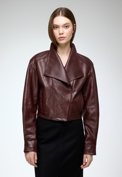 Burgundy leather cropped jacket with a wide collar, diagonal seams, and front button closure. Smooth texture, minimalistic design.