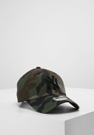 Casquette de baseball camouflage avec logo noir des New York Yankees brodé à l'avant et sangle réglable sur une surface d'exposition blanche.