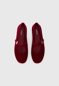 Sapatos Mary Jane de veludo vermelho com bico arredondado, uma tira sobre o peito do pé e uma palmilha acolchoada para conforto. Detalhe em metal dourado brilhante.