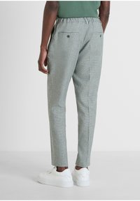 Pantaloni grigi a fantasia con vestibilità rilassata, vita elasticizzata e due tasche posteriori. Abbinati a sneakers bianche.