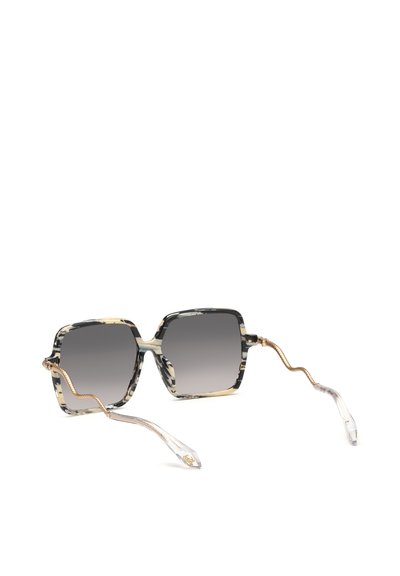 Lunettes de soleil carrées avec montures marbrées noires et blanches, verres foncés dégradés, et branches ondulées dorées se terminant par des embouts en plastique transparent.