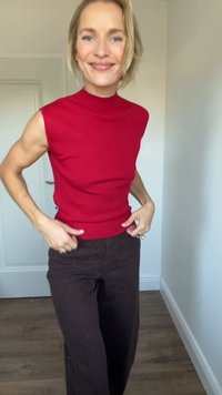 Red sleeveless top with high neck, paired with brown textured pants featuring a slight flare at the bottom and visible front pockets.
