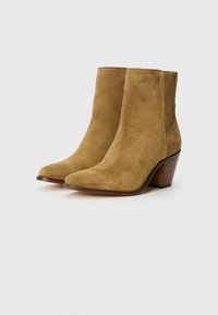 Stivali alla caviglia in suede tan con punta appuntita, tacco in legno impilato e pannelli elastici laterali per una facile calzata. Texture liscia e minimalismo nel branding.
