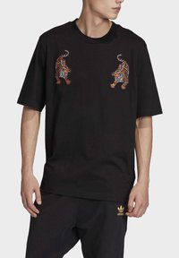 Svart bomull T-shirt med två broderade tigermönster på bröstet. Kort ärm och rund halsringning, med en lös passform.