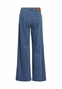 Jean en denim bleu à jambes larges avec taille haute, poches arrière, passants pour ceinture et un patch de marque en cuir marron sur la ceinture.