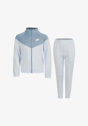 Lichtblauw en grijs Nike trainingspak met ritsvest en broek met elastische tailleband, beide met witte Nike-logo's aan de linkerkant.