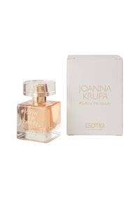 Przezroczysta szklana butelka z złotym akcentem i okrągłą zakrętką, zawierająca jasnobrązowy perfum. Biała pudełko z nazwą marki i produktu.