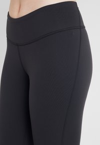 Svarta högmidjade leggings gjorda av stretchigt tyg med subtila ribbingar, med en platt midja och förstärkt sömnad längs sömmarna.