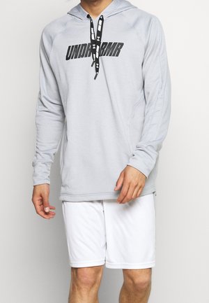 Jasnoszara bluza z długim rękawem z czarnymi sznurkami i wyraźnym czarnym logo "UNDER ARMOUR". Nosi się z białymi szortami sportowymi. Miękki, aktywny materiał.