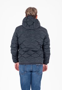 Giubbotto imbottito nero con cappuccio caratterizzato da un motivo a rombi trapuntato. La parte posteriore presenta un tessuto testurizzato e un orlo aderente. Abbinato a jeans blu.