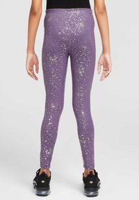 Leggings morados con un patrón brillante salpicado en plata, de cintura alta y textura suave, combinados con zapatillas deportivas negras.