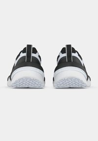 Αθλητικά παπούτσια ασπρόμαυρα, σε κάτοψη από πίσω, με υφή στη σόλα, επενδυμένο κολάρο και θηλιά έλξης.