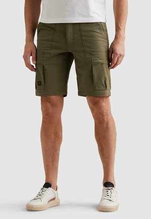 Man draagt olijfgroene cargoshorts met grote zijzakken, een wit t-shirt en witte sneakers met zwarte details.